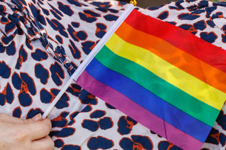 Seated woman in spotted dress holding LGBT rainbow flag on Her lap