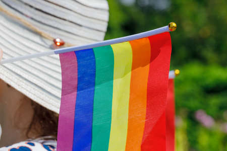 A woman in a stylish summer hat with a flag supporting the LGBT movement on her shoulderの写真素材
