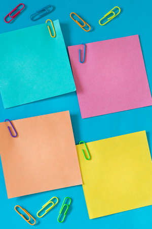 small colored sticky notes with office staples and space for text, Blue backgroundの写真素材
