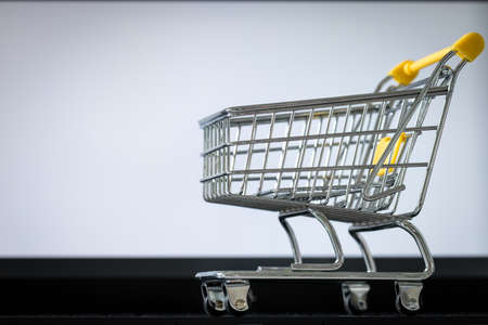 shopping cart on laptop keyboard. White monitor screen with space for text. Concept of online shopping and online storesの写真素材