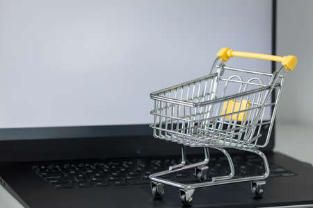 shopping cart on laptop keyboard. White monitor screen with space for text. Concept of online shopping and online storesの写真素材