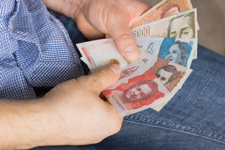 a man holding a bundle of money in his hands, various Colombian pesosの写真素材