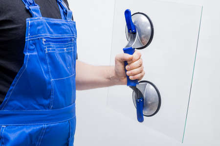 Glazier holding a transparent glass on the suction cup, White backgroundの写真素材