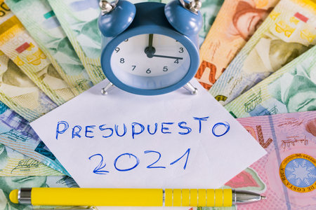 Costa Rica money and a card with handwritten words in Spanish. Budget 2021 Next to it is a five...