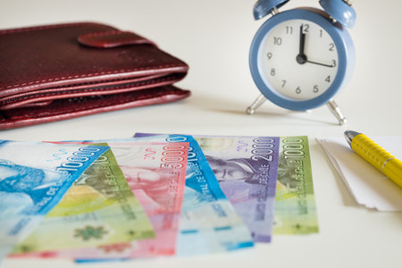 Chile currency, pesos, next to the wallet and the clock showing five to twelveの写真素材