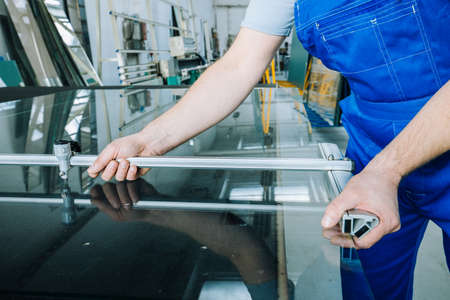 The glazier's worker cuts the glass with a special tool. Glassworksの写真素材