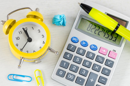 calculator and alarm clock for five to twelve. Office accessories. Concept, Accounting, Deadlineの写真素材