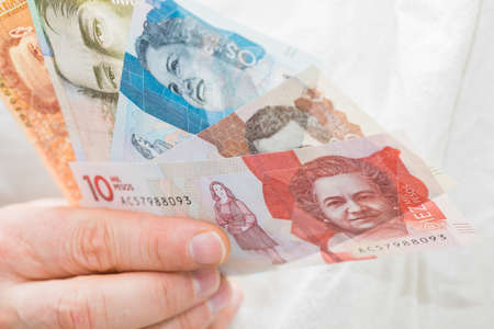 Colombian pesos. Money held in a man's hand
