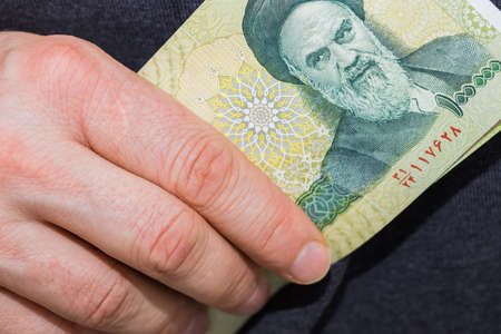Iranian one hundred thousand rial banknote, held in a man's handの写真素材