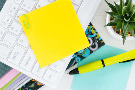 Yellow sheet of paper with space for text. Office accessories, computer keyboard, pens, documents on the deskの写真素材