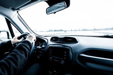 Driving a car on a snow-covered road. View from inside the car while driving in winterの写真素材