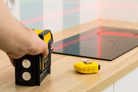 A professional checks the angles while taking measurements of the kitchenの写真素材