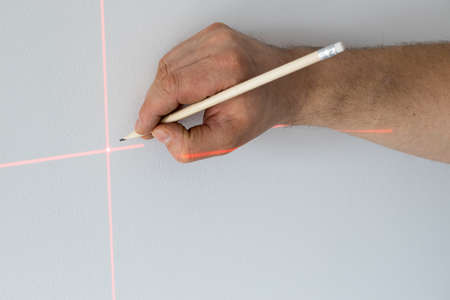 A specialist marks a point on a wall with an electronic laser
