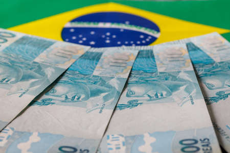 Brazilian money, one hundred reais banknotes on the background of the national flag. Country economy conceptの写真素材