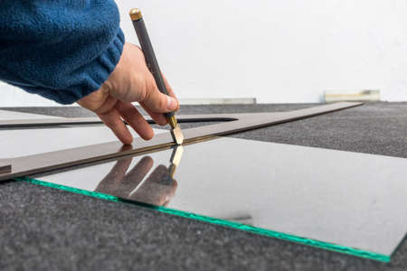 The glazier cuts the glass with a hand-held cutting tool. Handicraft plant, Close up