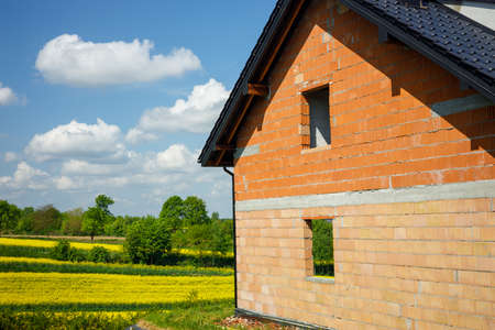 Construction of a country house, Construction of a newly emerging building against the backdrop of flowering fields and meadows. The concept of moving out and living outside the cityの写真素材