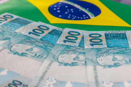 Brazilian money, one hundred reais banknotes on the background of the national flag. Country economy conceptの写真素材