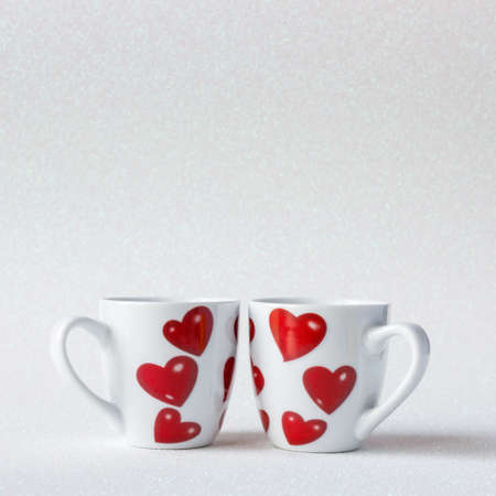Two cute cups with hearts, shiny bright background, decorative layout, love concept, romantic mood, place for textの写真素材