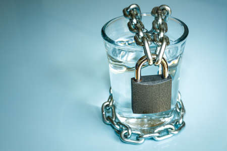 a glass of water wrapped in a chain and closed with a padlock. the problem of small drinking water resources in the world. Environmental protection conceptの写真素材