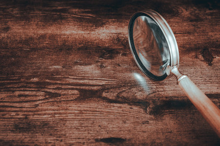 Stylish magnifying glass with a wooden handle, standing on a similar color table top, empty spaceの写真素材