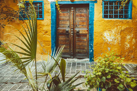 Historic architecture, Stylish doors with brass fittings, a blue frame and shutters against the background of a yellow wall and green plantsの写真素材