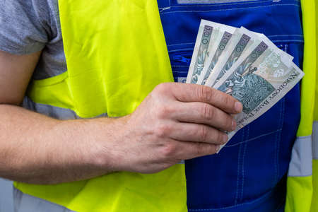 Worker counting his earnings, Polish money, Concept of wages and labor costs in industryの写真素材