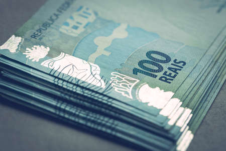 Large bundle of Brazilian money, 100 reais banknotes, gray backgroundの写真素材
