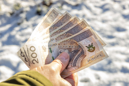 held in hand Polish money, 200 zlotys banknotes, On the background of snow. The concept of inflation and price increases with the new yearの写真素材