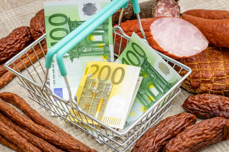 One hundred and two hundred Euro banknotes in an empty shopping basket, around various types of meats, Concept, Rising prices of meat products and food in European Union countriesの写真素材