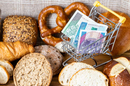 Shopping basket with Polish money, around food products, bread and cookies. The concept of inflation, rising prices and more expensive foodの写真素材