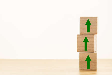 Wooden blocks lined up in a column with green arrows pointing upwards, Concept of growth and effective developmentの写真素材
