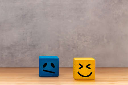 Positive and negative reactions, Change of attitude, creative concept, business and personal development, Blue brick with painted sad emoticon and yellow brick with a happy smileの写真素材