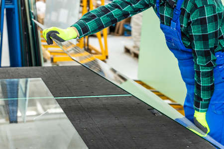 The glazier places a pane of glass on a specialized table, Work in a glass factory