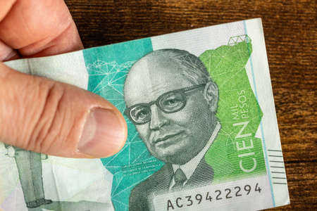 Colombian 100 pesos, held in hand, Highest denomination