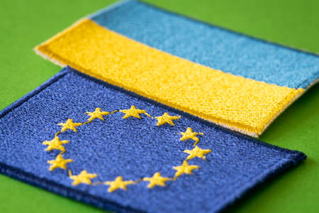 Concept of Ukraine joining the European Union, Ukrainian national flag next to the EU symbol lying...