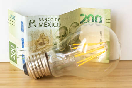 Mexican 200 pesos and a light bulb, Concept of rising energy and electricity prices in Mexico