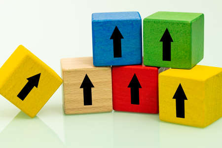 colored wooden blocks with growth arrows arranged in the shape of a pyramid, one block at the bottom showing the way to the top, Stable development conceptの写真素材