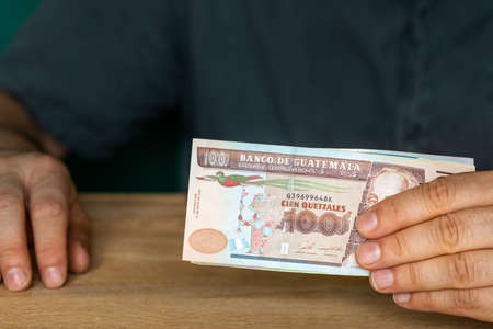 Guatemala currency, A man in a shirt holds money in his hands, financial settlements, Creative...