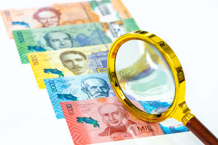 Costa Rica money, flat lay, all banknotes unfolded, magnifier, white background