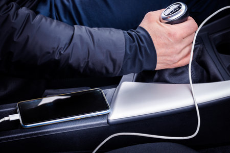 charging the phone in the car. A smartphone connected to a charger and lying in a dangerous place...