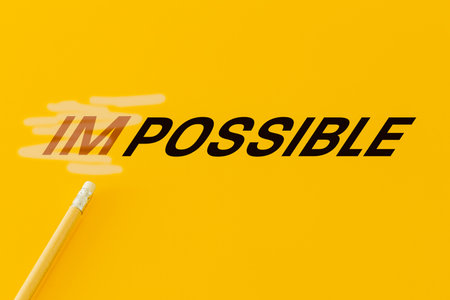 Concept of positive thinking, word impossible erased with an eraser and changed to possible, yellow backgroundの写真素材