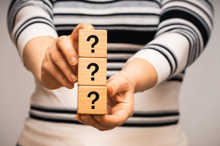 a woman holds wooden blocks with question marks in her hands, The concept of the unknown, looking...