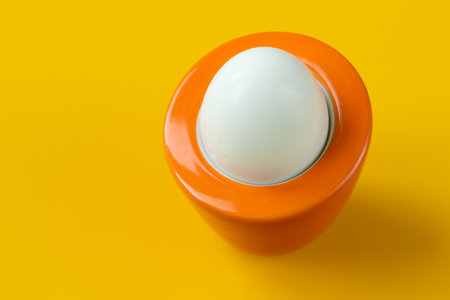 boiled egg in an orange stand on a yellow background, original design, the concept of reviving,...