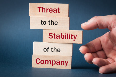Threat to the stability of the company, Business concept, text on wooden blocks, Hand taking a block with the inscription Stability from the tower, analysis of the company's financial situationの写真素材