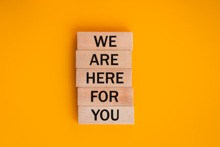 we are here for you, Written on wooden blocks, words to live by, Business idea. invitation to cooperation, support concept, beautiful yellow backgroundの写真素材