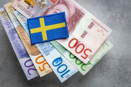 Sweden flag lying on a bundle of swedish kronas, Currency of Sweden, business and financial conceptの写真素材