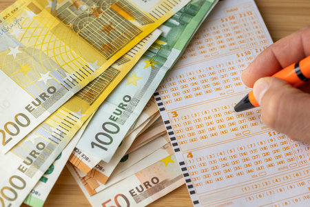 European lotteries, Lottery ticket, Stack of Euro banknotes, Hand with pen, Crossing out lucky numbers, Winning the drawの写真素材