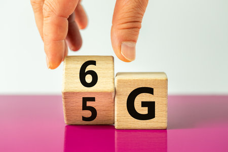 time for the 6G symbol. The hand rotates the wooden cube and changes the 5G sign to 6G. Concept, technology development, high speed communication network and 6g. Beautiful fuchsia and white backgroundの写真素材