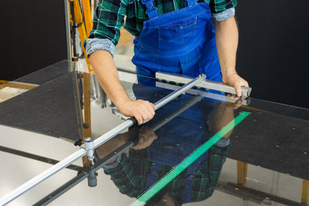 Glass glazier, cuts glass panes with specialized tools, Glass factoryの写真素材