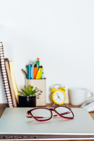 the closed notebook was placed on the desk in the room, women's glasses put away, vertical photo, copy spaceの写真素材